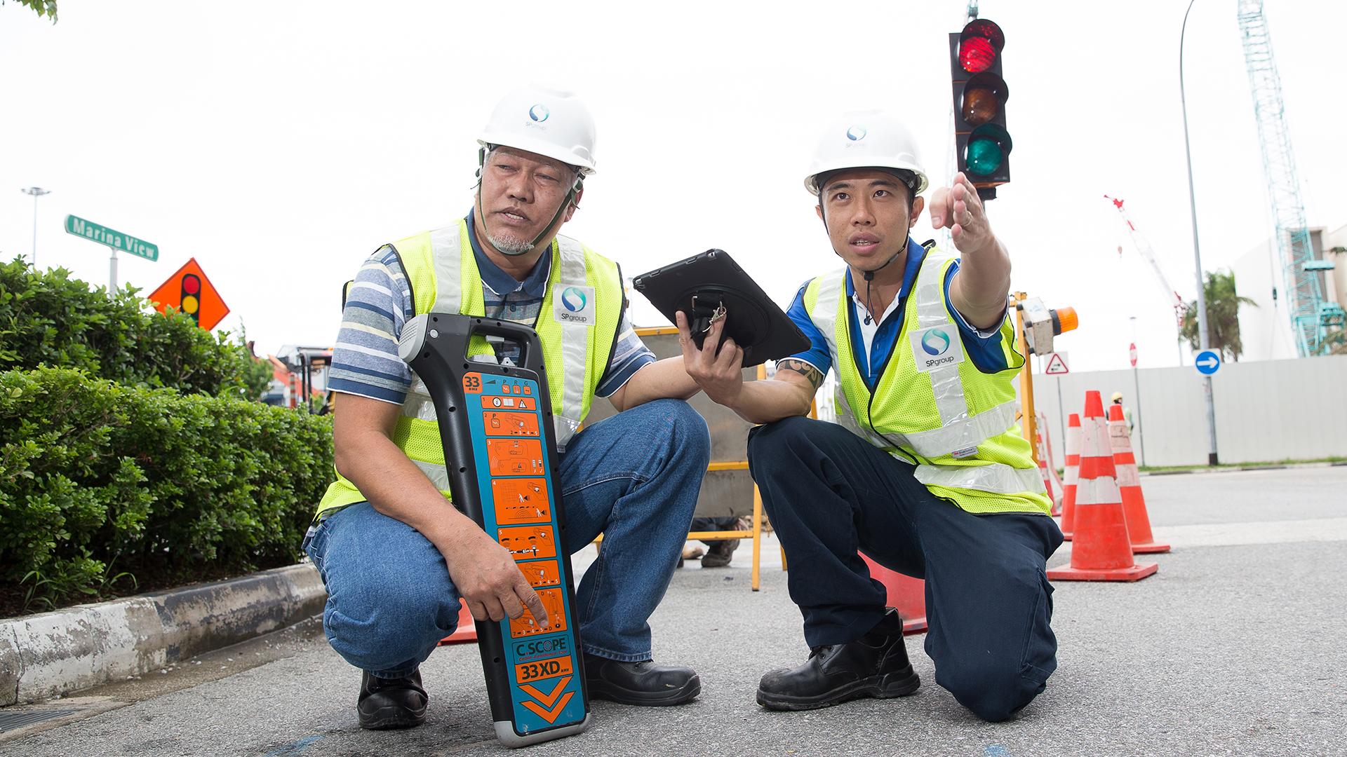 Detect and protect: Technical officer Mohamed Saiful Matsaid (left) uses a cable locator to detect electricity cables hidden underground as Principal Engineer James Ou (right) marks out the path of the cable.