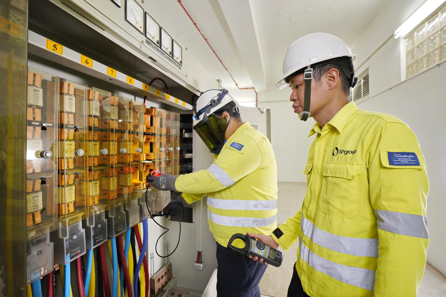 (From right) Principal Engineer Jerome Choong supervising Technical Officer Arif Tham during the checking of a Low Voltage (LV) board, to maintain substation equipment.